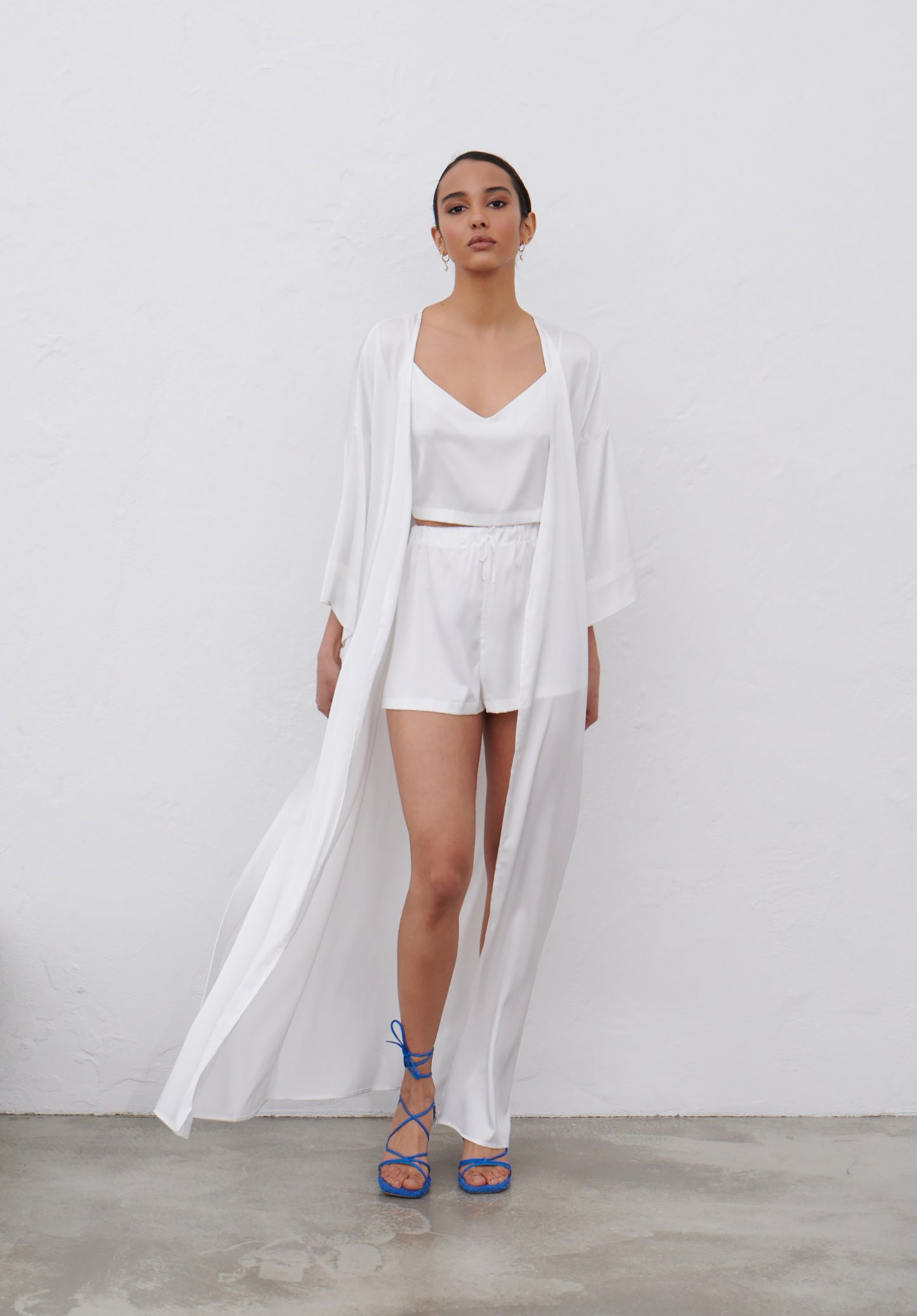 Model in white satin pajamas set with camisole top and shorts