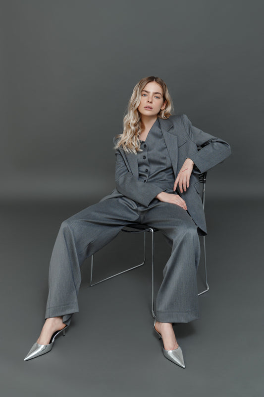 Model wearing gray palazzo pants with matching blazer.