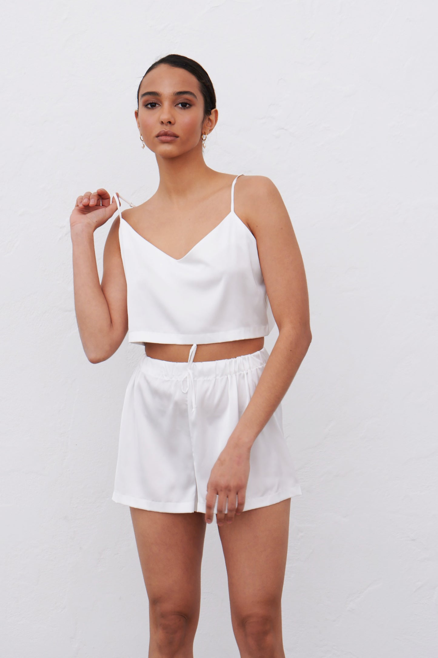 Model wearing white satin pajamas camisole and shorts